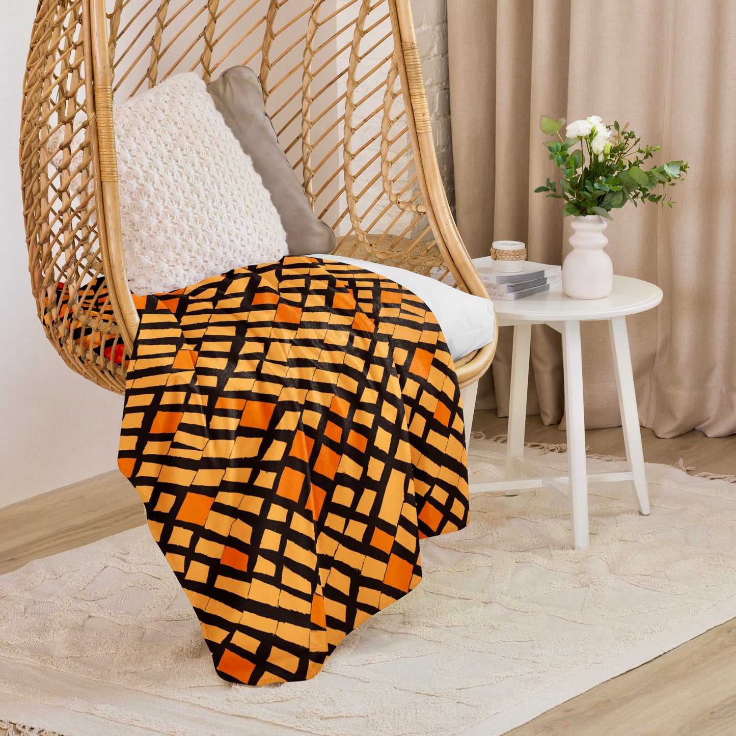 Chic orange Lagos Sherpa blanket in a captivating abstract design draped over a hanging wicker chair, infusing a creative and cosy element into a modern home setting.