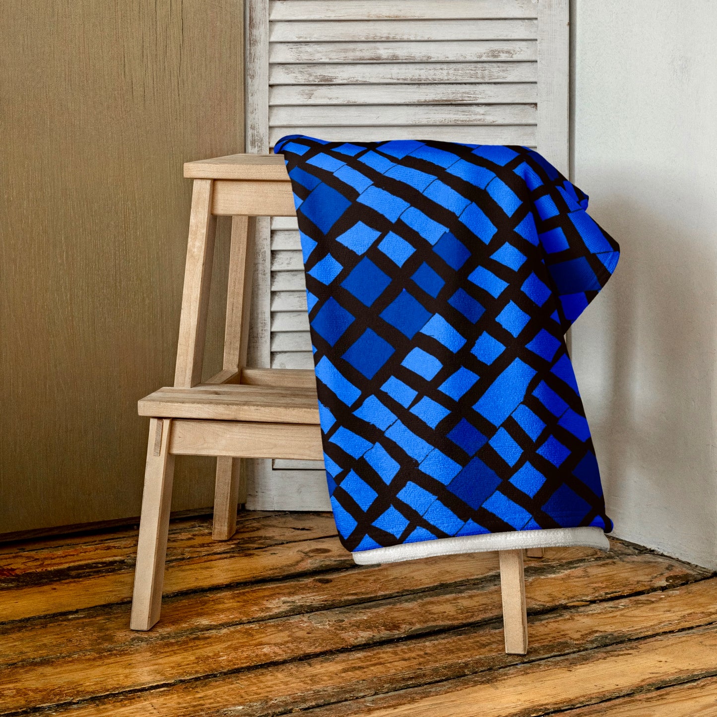 Crisp blue Lagos beach towel from Tintin Studios, neatly folded on a wooden stool, displaying its pure and elegant design.