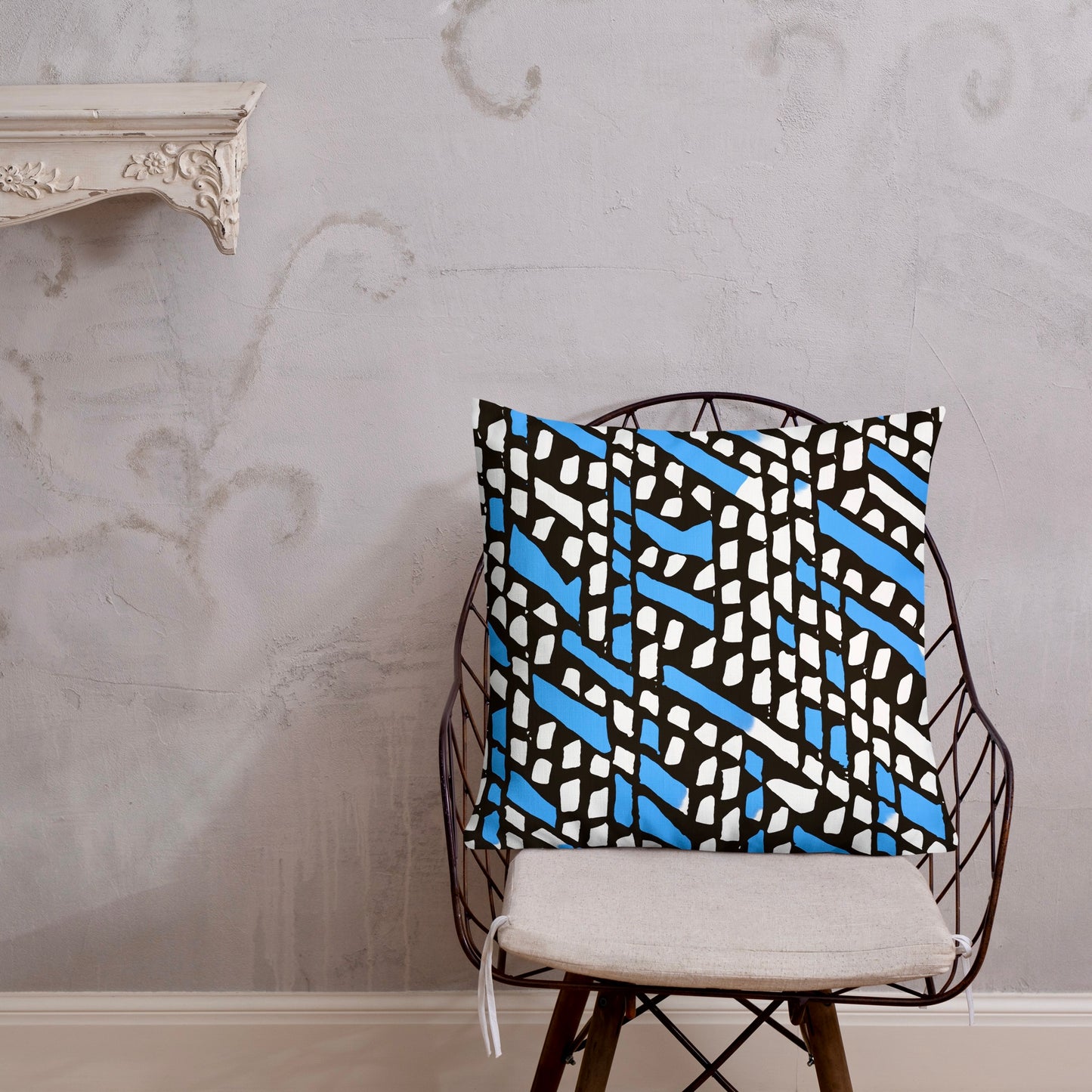 22x22 Ilorin blue throw pillow from Tintin Studios, showcasing extensive earthy designs on a black iron chair.