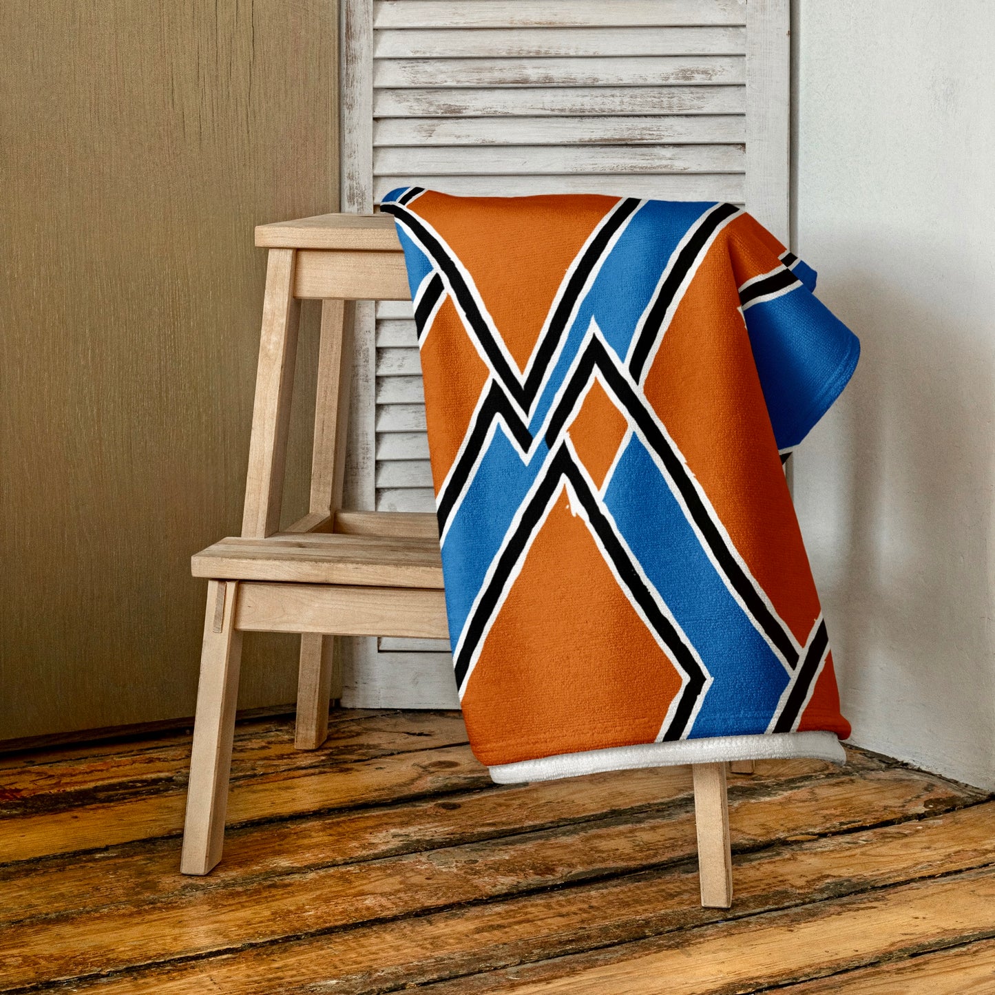 Brown Nana towel from Tintin Studios folded neatly and placed on a wooden stool, highlighting its rich, warm colors and culturally inspired patterns, offering a sense of rustic elegance.