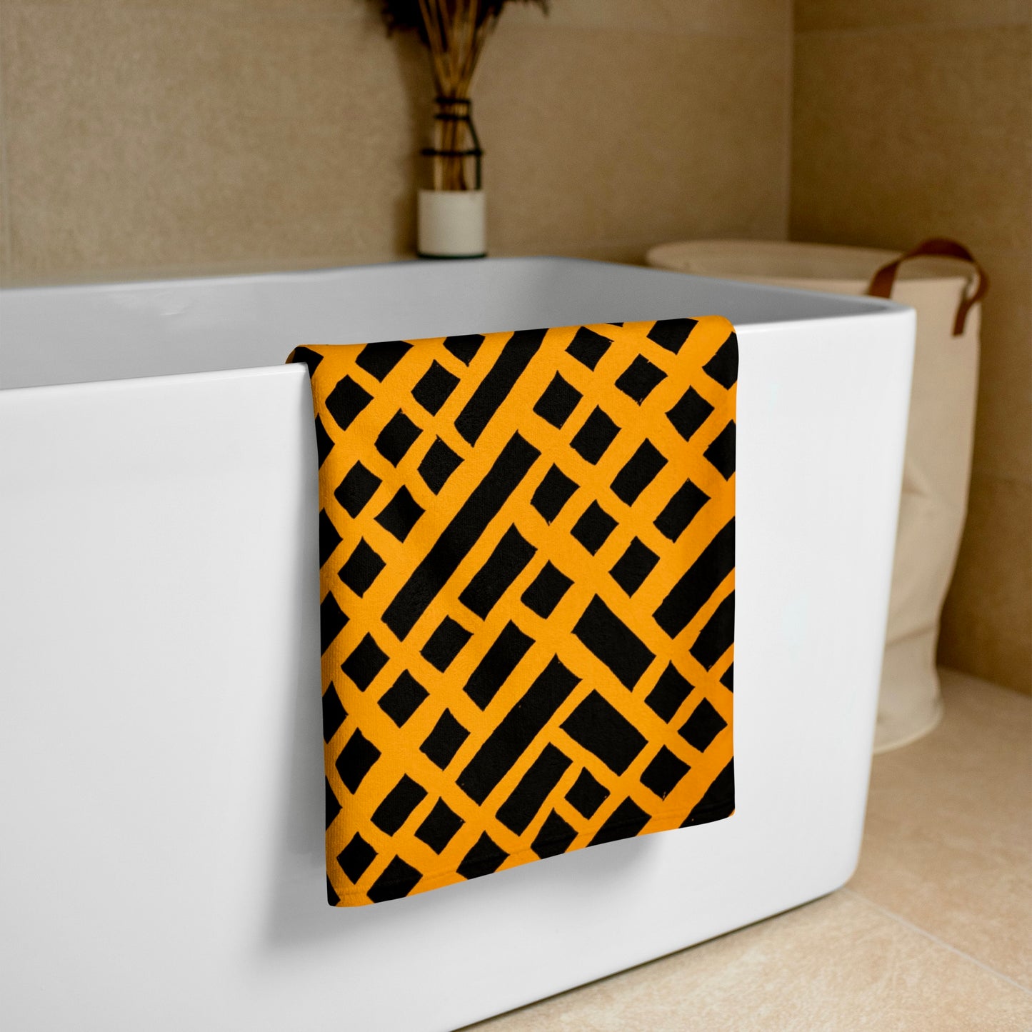 Orange Felele beach towel from Tintin Studios elegantly draped over a white bathtub, emphasizing its vivid cultural motifs and luxurious feel.