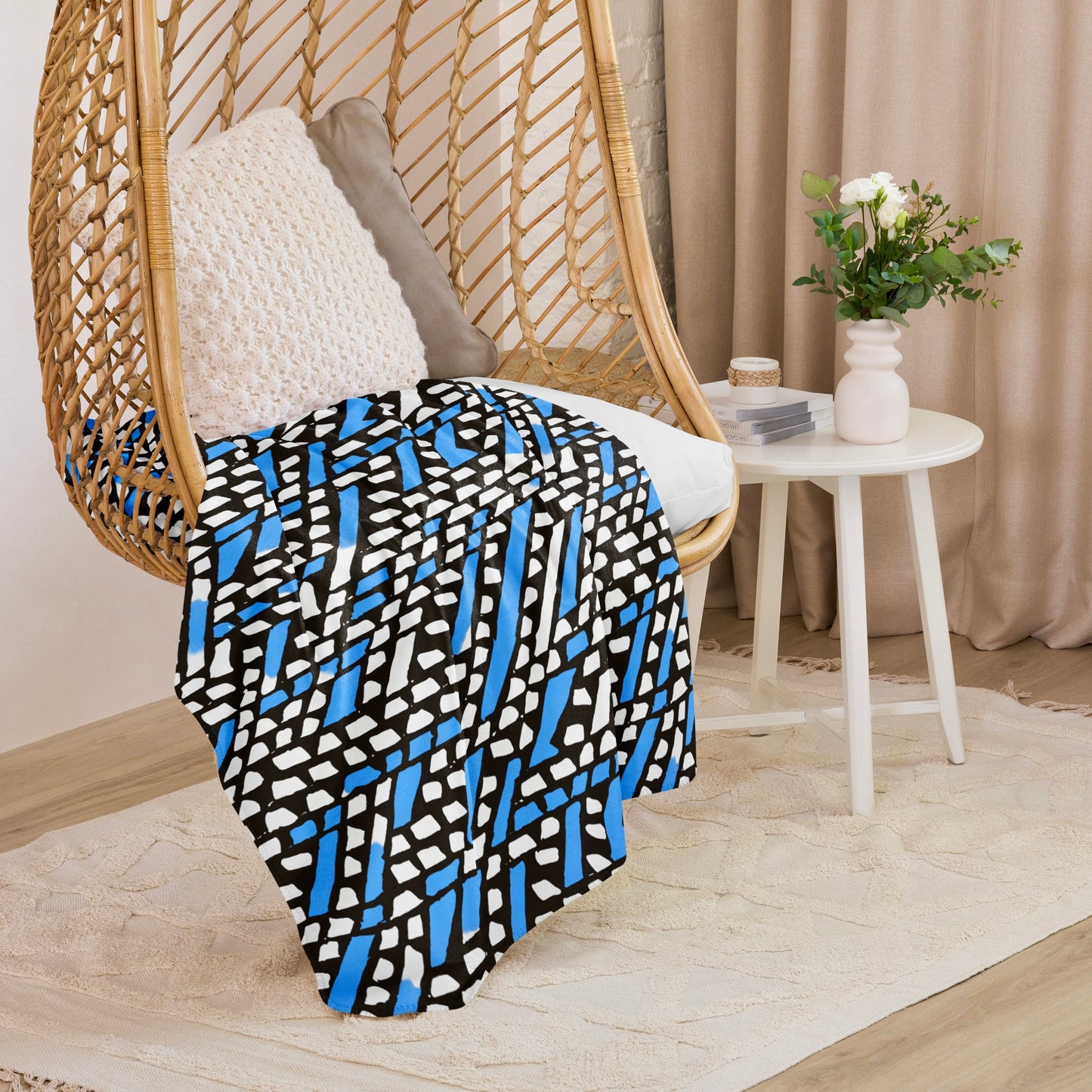 Blue Ilorin Sherpa blanket from Tintin Studios displayed on a wicker chair, its soothing blue tones and rustic designs offering tranquility and style.