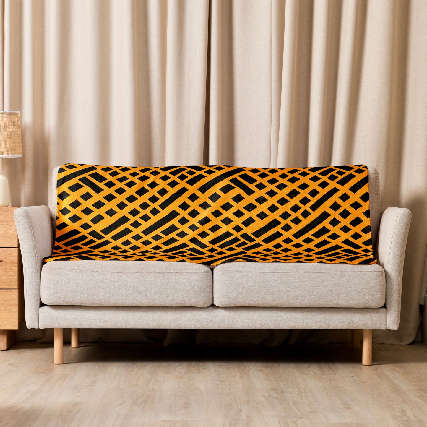 Warm orange Felele Sherpa blanket draped over a cream couch, perfectly blending with the room’s decor to create an inviting and stylish living space.