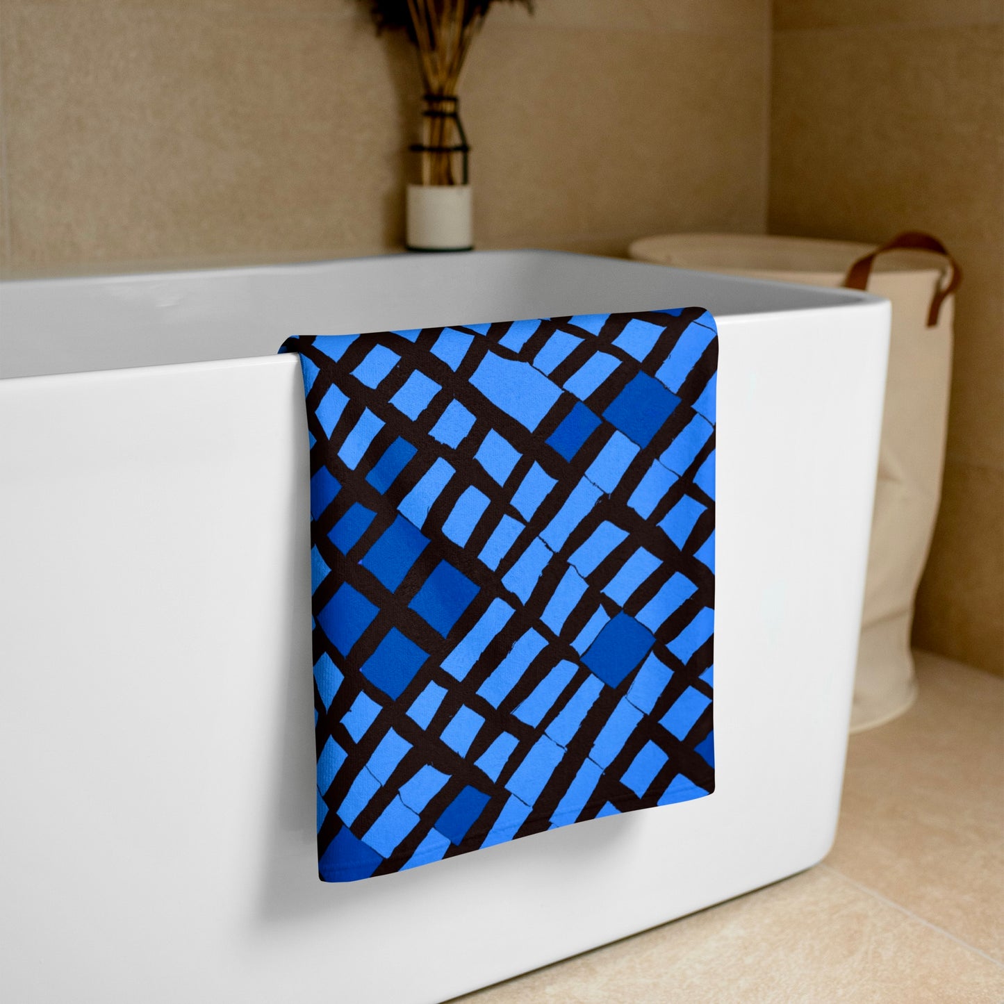 Blue Lagos beach towel from Tintin Studios draped over a white bathtub, highlighting its pristine appearance and modern charm.