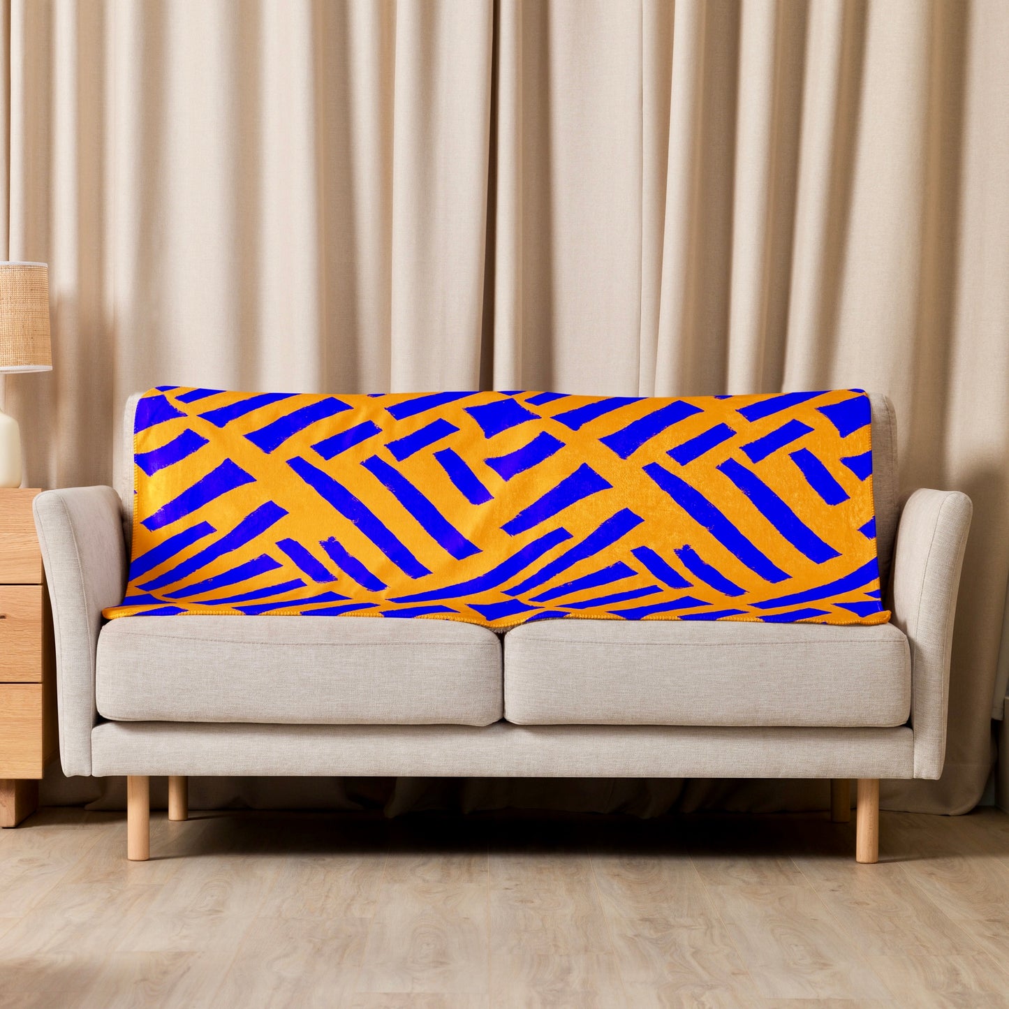 Tintin Studios' blue Tutu Sherpa blanket with vibrant abstract designs thrown casually over a cream couch, providing a pop of colour and artistic flair to the living area.