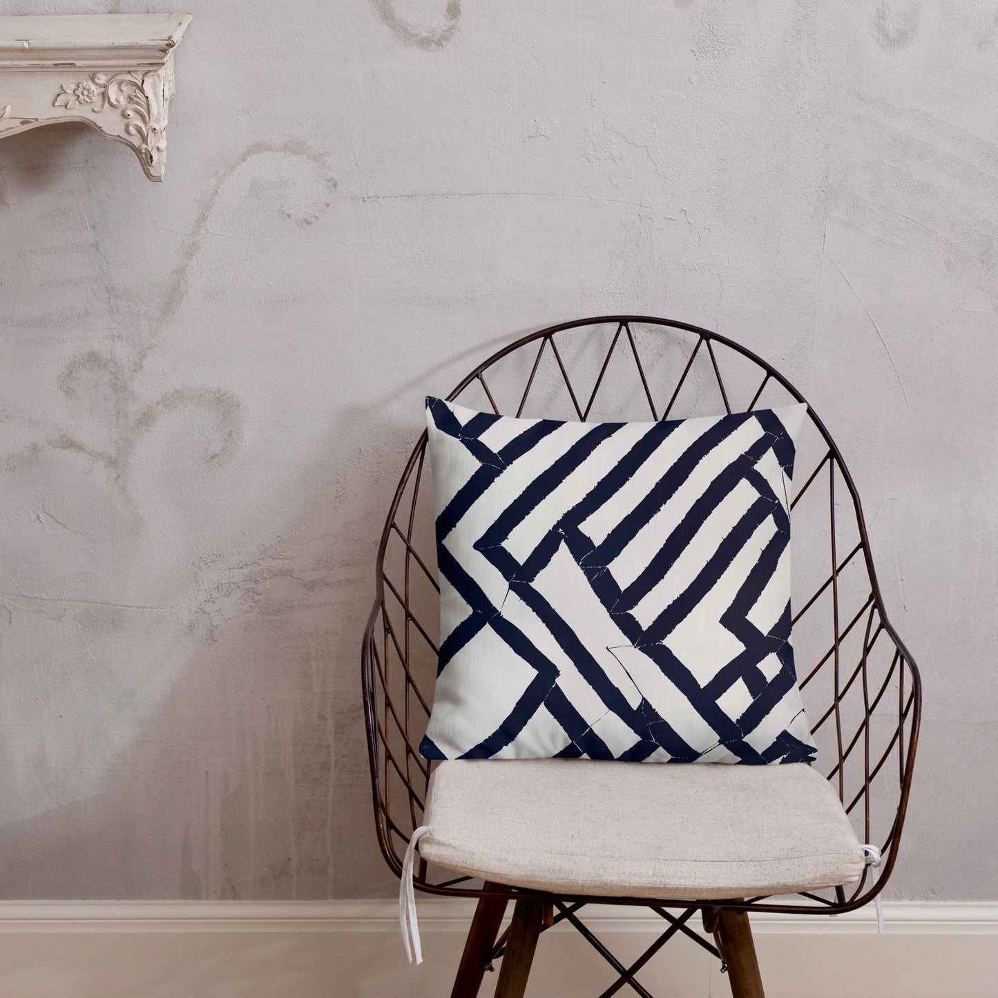 18x18 Lokoja blue throw pillow from Tintin Studios on a black iron chair against a grey wall, featuring dynamic geometric patterns.