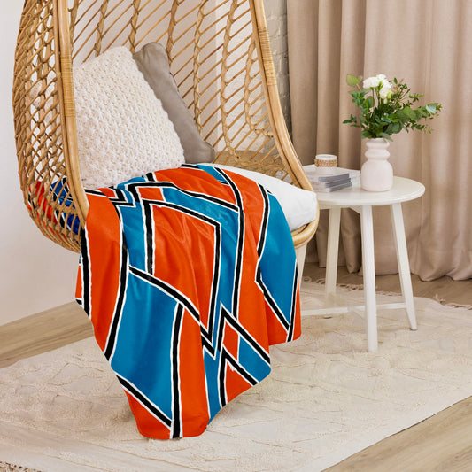 Colourful  red Nana Sherpa blanket from Tintin Studios elegantly draped over a wicker hanging chair, adding a warm, vibrant touch to a stylish corner setup.