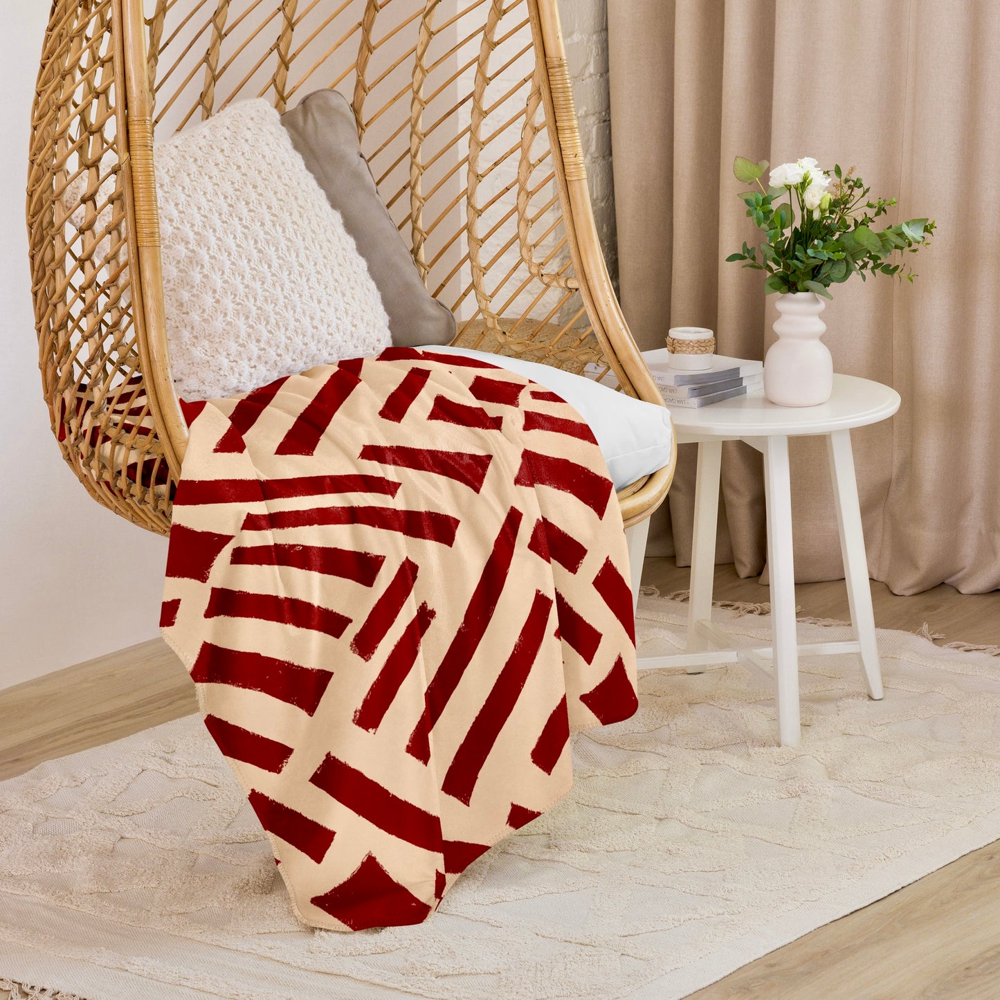 Artistic red Tutu Sherpa blanket from Tintin Studios in a captivating abstract design draped over a hanging wicker chair, infusing a creative and cosy element into a modern home setting.