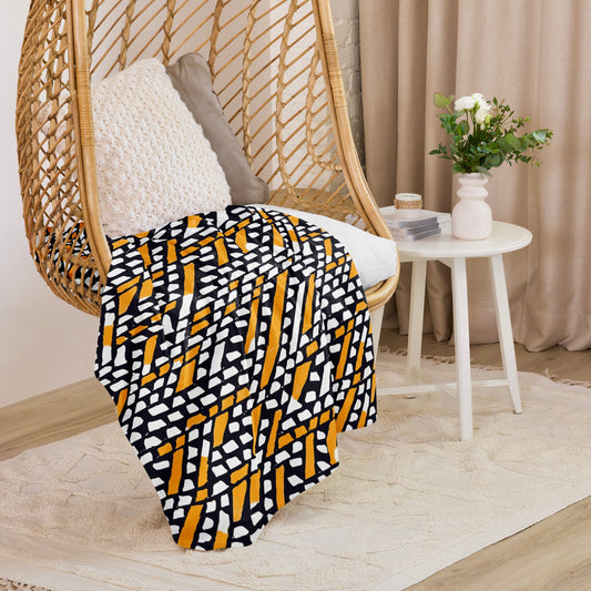 Earthy orange Ilorin Sherpa blanket from Tintin Studios hanging on a wicker chair, with rustic patterns ideal for adding a natural touch to any room.