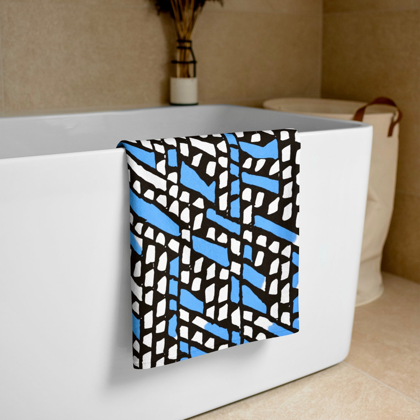 Blue Ilorin beach towel from Tintin Studios, elegantly draped over a white bathtub, displaying its inviting texture and natural motifs.