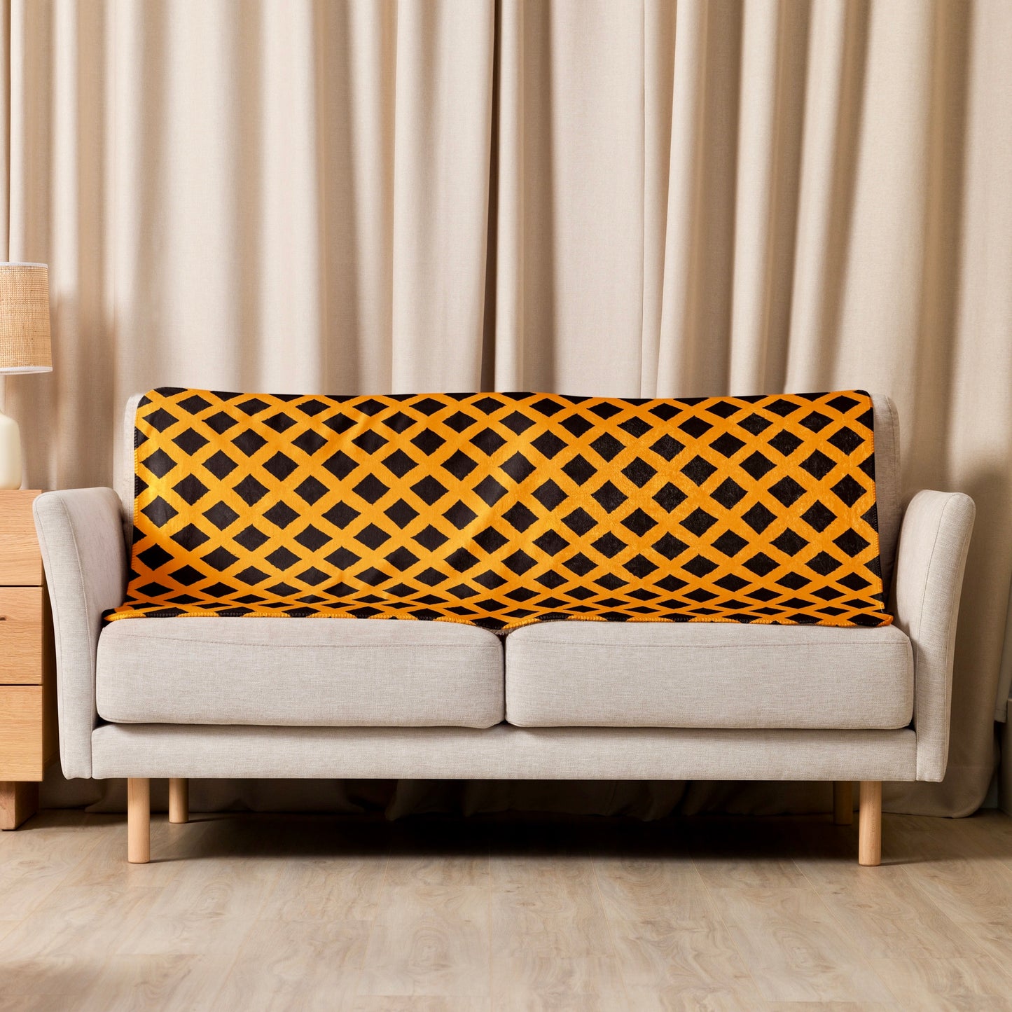 Orange Zaria Sherpa blanket from Tintin Studios draped elegantly over a cream couch, its earthy patterns and rich texture creating a cosy retreat.