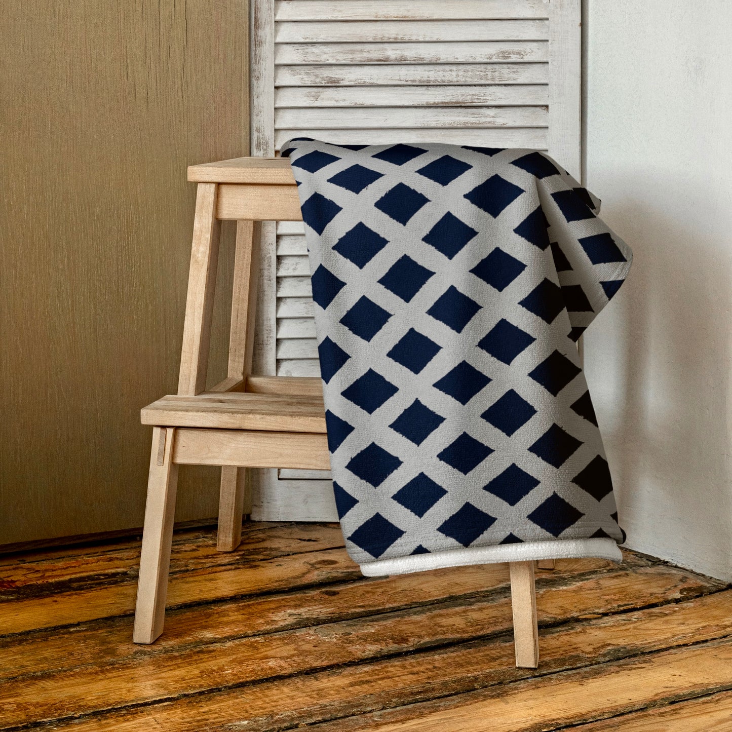 Blue Zaria beach towel from Tintin Studios folded on a wooden stool, showcasing its soothing blue shade and minimalist design, perfect for a serene beach or home setting.