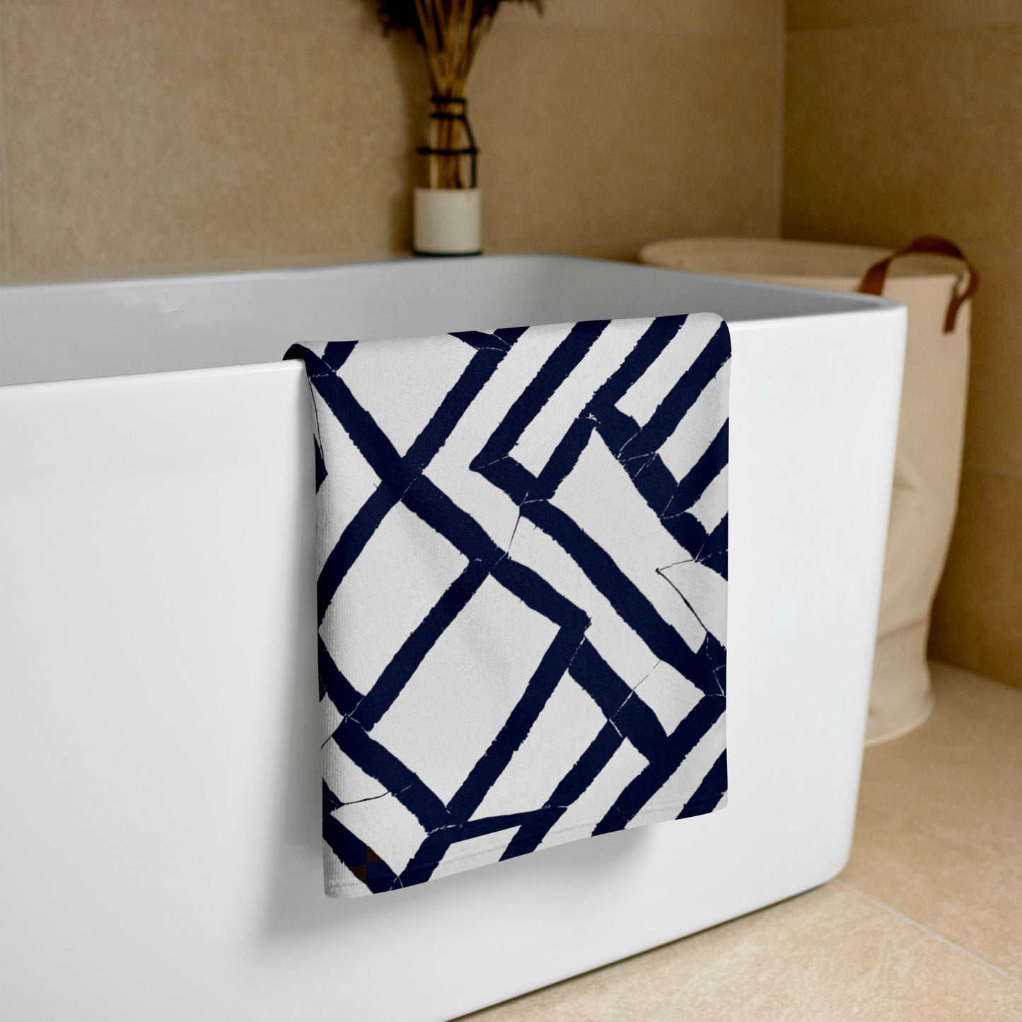 Elegantly folded blue Lokoja beach towel from Tintin Studios placed on a white bathtub, accentuating its chic design and practical elegance.