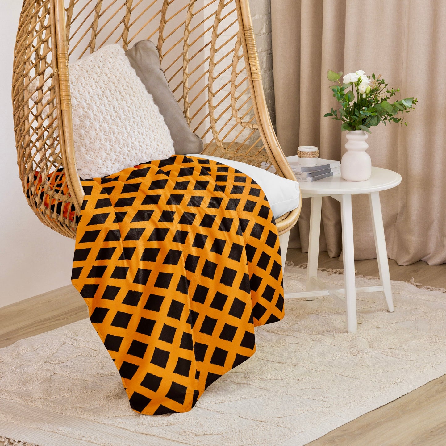 Earthy orange Zaria Sherpa blanket from Tintin Studios hanging on a wicker chair, with serene patterns ideal for adding a calming touch to any room.