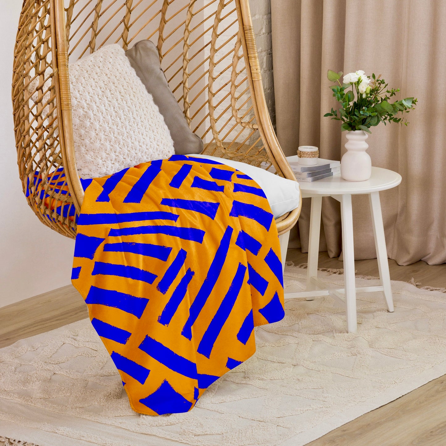 Artistic blue Tutu Sherpa blanket from Tintin Studios in a captivating abstract design draped over a hanging wicker chair, infusing a creative and cosy element into a modern home setting.