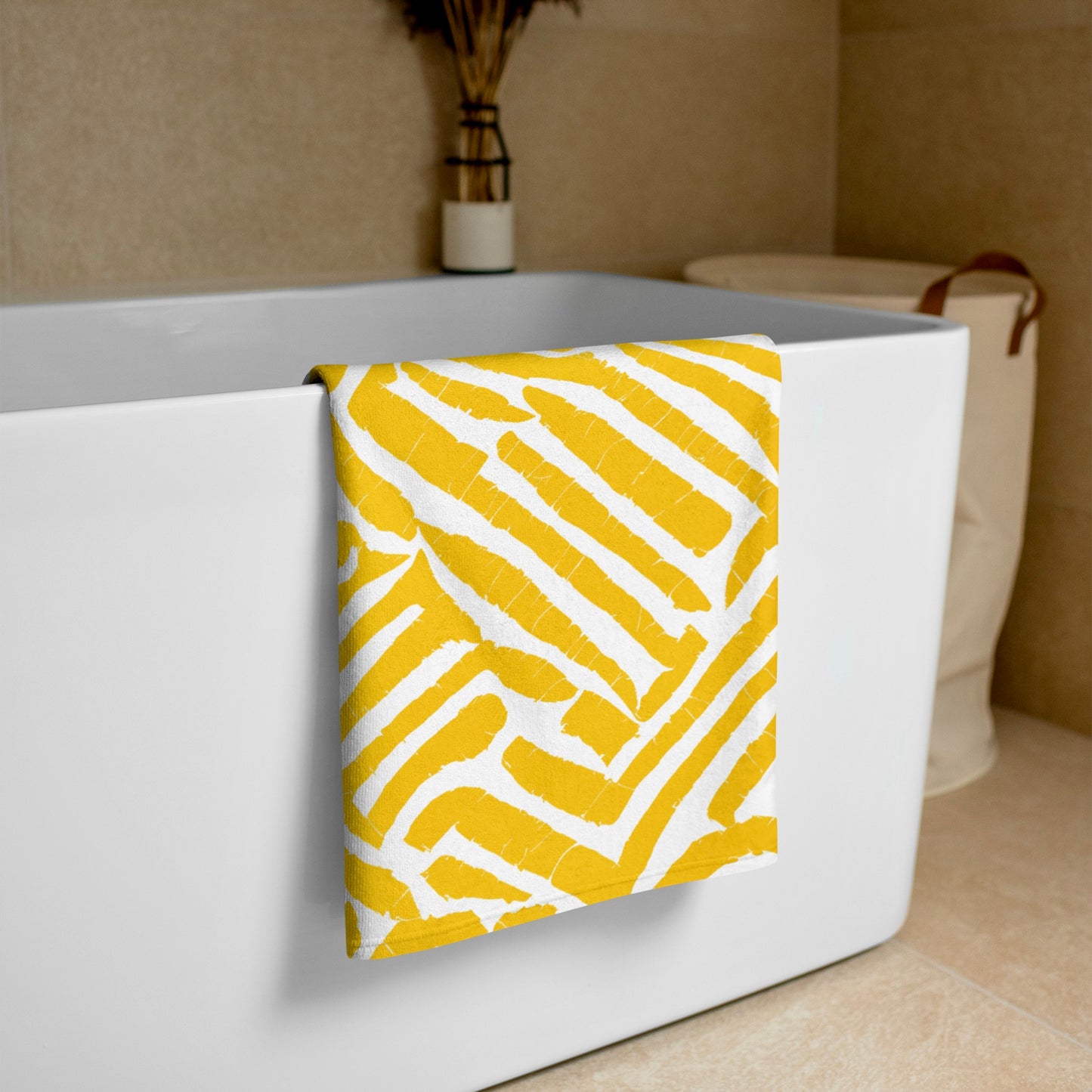 Elegant yellow ChiChi beach towel from Tintin Studios elegantly draped over a white bathtub, emphasizing its chic patterns and premium texture.