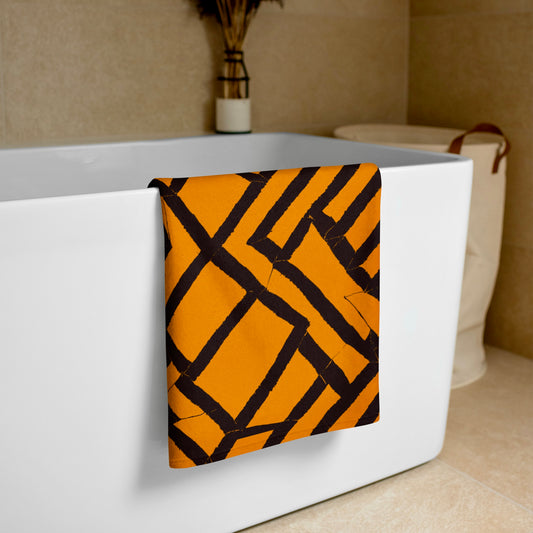 Softly folded orange Lokoja beach towel from Tintin Studios, resting on the edge of a white bathtub, offering a glimpse of luxury and functionality.