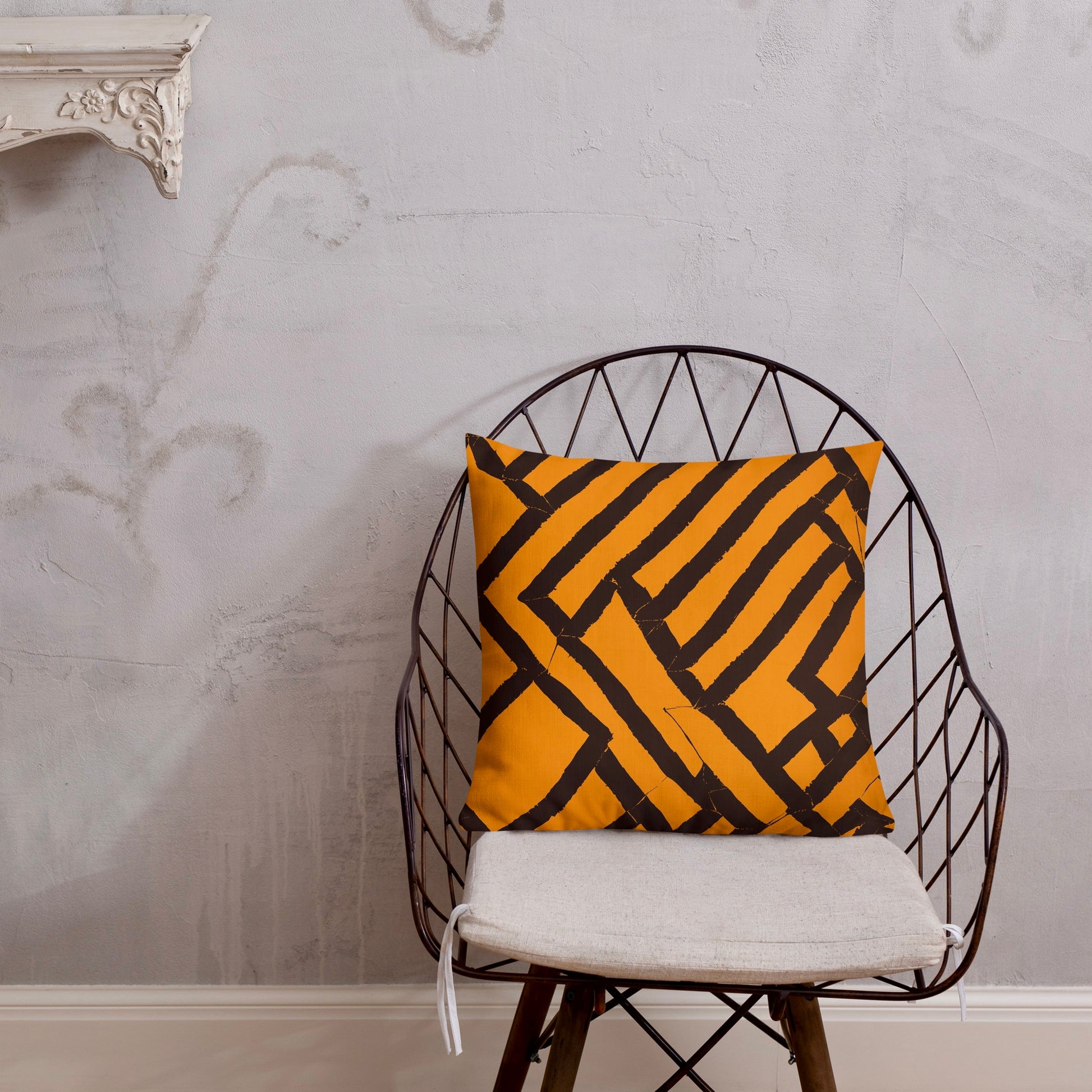 18x18 Lokoja orange throw pillow from Tintin Studios on a black iron chair, vivid and eye-catching.