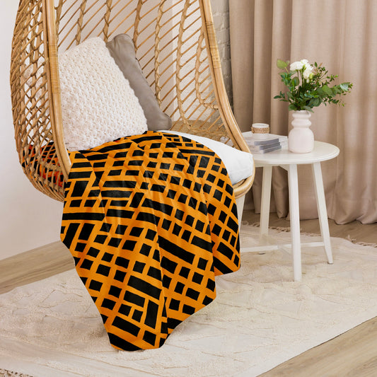 Tintin Studios' Felele Sherpa blanket in rich orange draped elegantly over a wicker hanging chair, adding a touch of earthy warmth to a cosy, modern nook with a white side table and elegant curtains in the background.