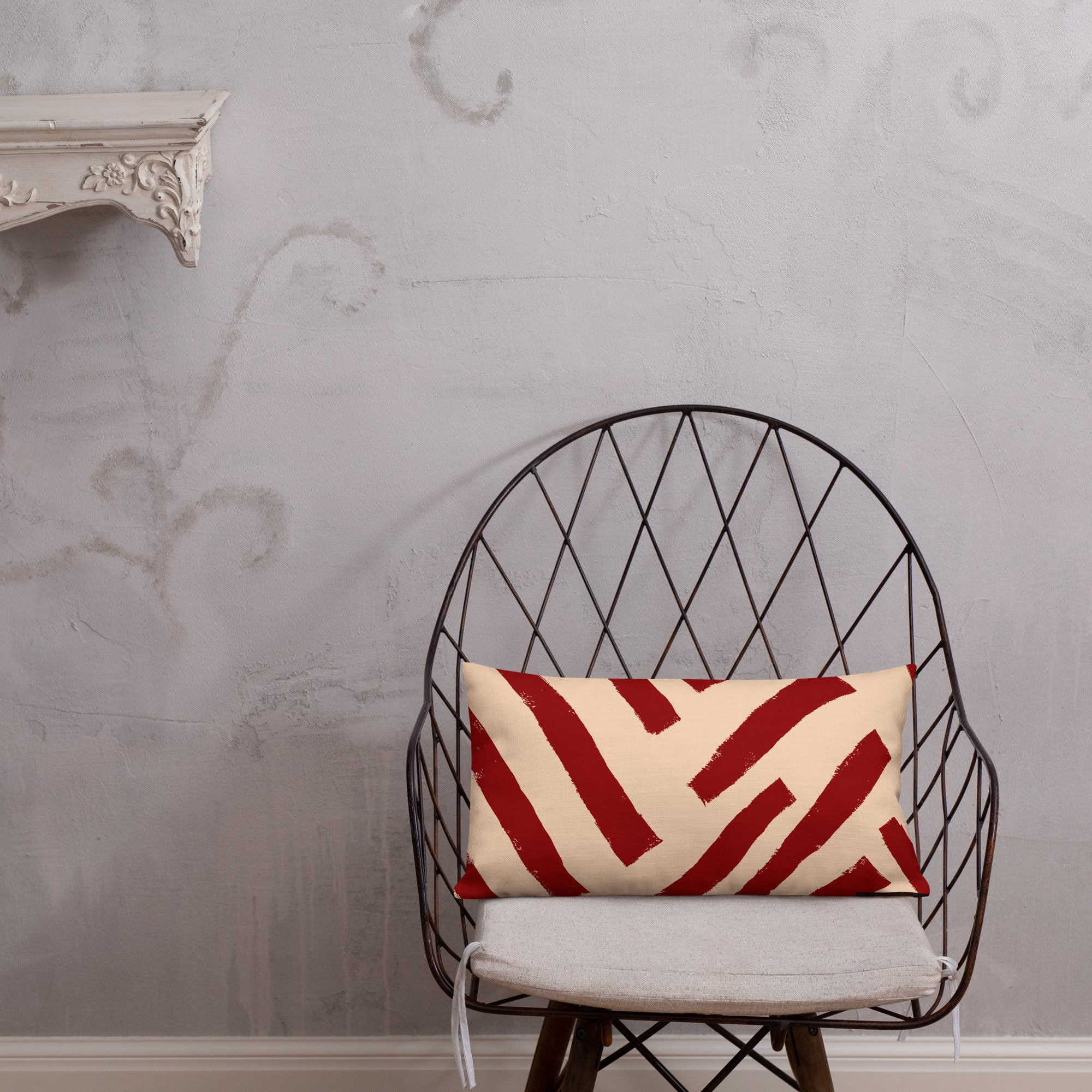 Vibrant red rectangular Tutu throw pillow from Tintin Studios positioned elegantly on a black iron chair, set against a muted grey wall. The pillow features distinctive abstract patterns, offering a striking contrast that enhances any modern decor.